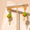 displayed green olive hoop dangle earrings with a gold 'toothpick' through it