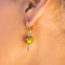 up close of model wearing green olive hoop dangle earrings with a gold 'toothpick' through it