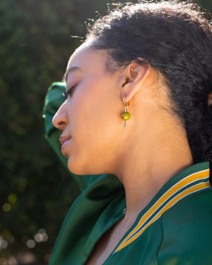 model wearing green olive hoop dangle earrings with a gold 'toothpick' through it