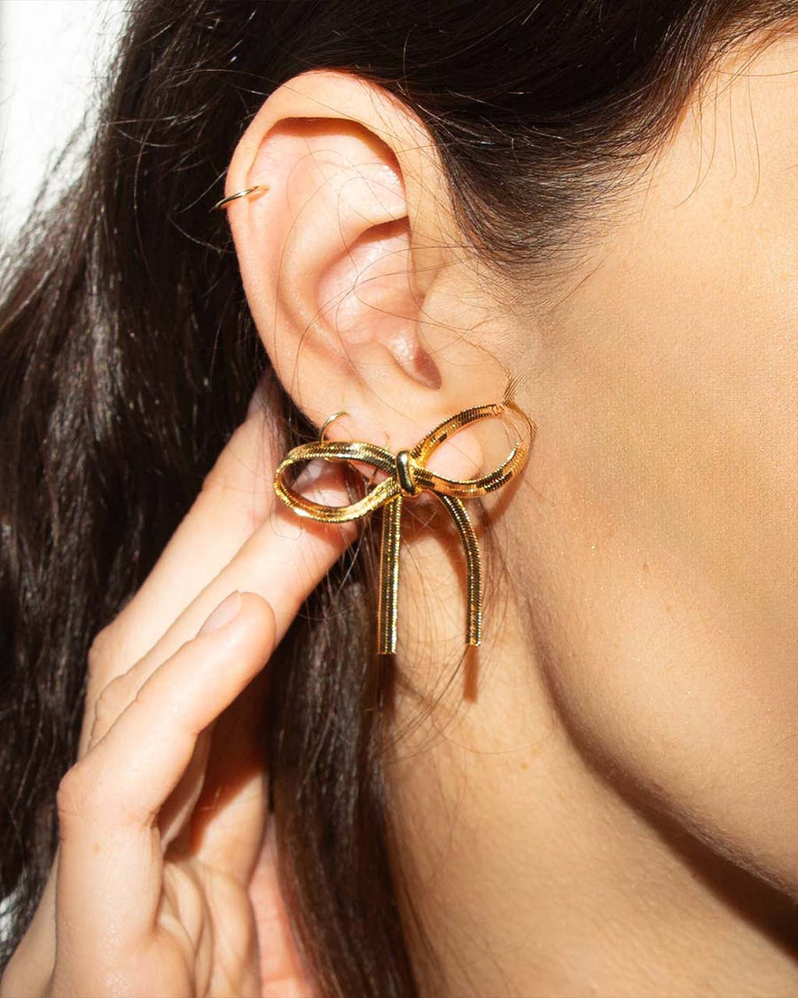 model wearing thick gold bow earrings