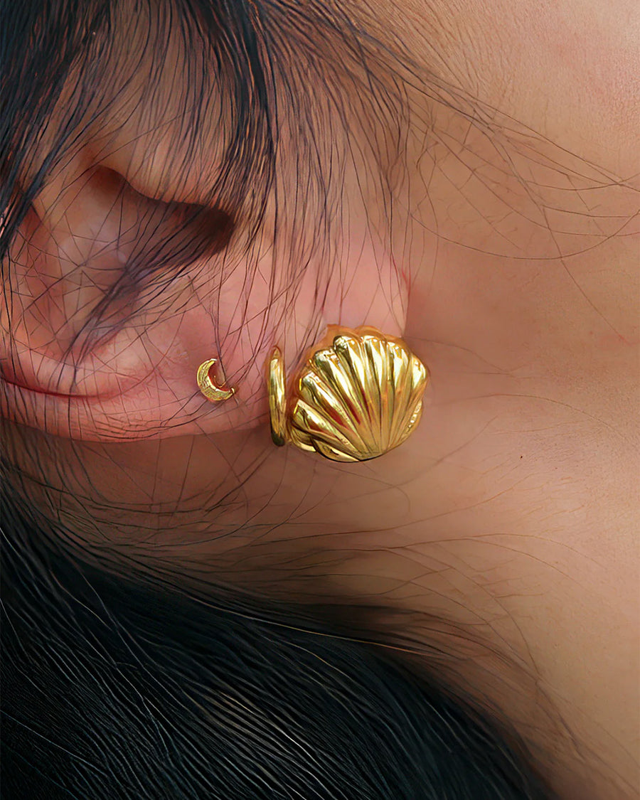 model wearing gold seashell huggie earrings