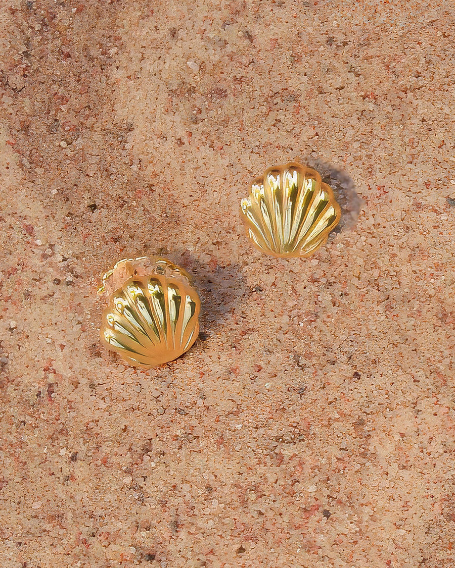 gold seashell huggie earrings in the sand