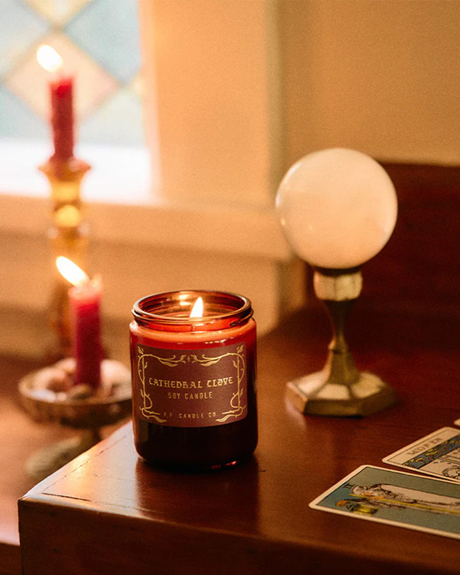 cathedral clove standard candle with ed jar and gold lid on a wooden table