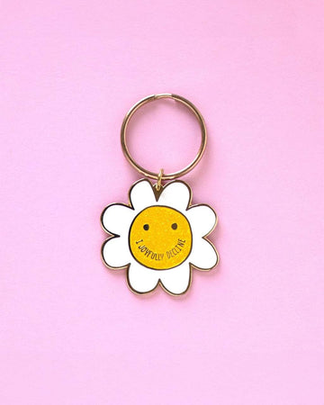white daisy shaped enamel keychain and smiley face with 'i joyfully decline' as the mouth
