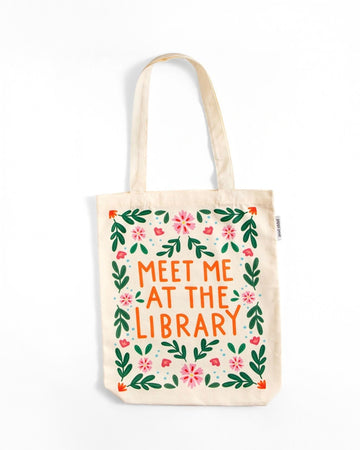 tan canvas bag with orange 'meet me at the library' surrounded by colorful flowers
