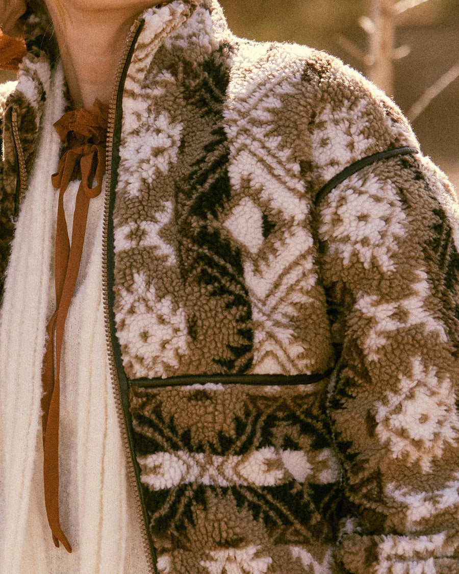 up close of model wearing brown and white geometric zip up sherpa sweatshirt with faux leather trim
