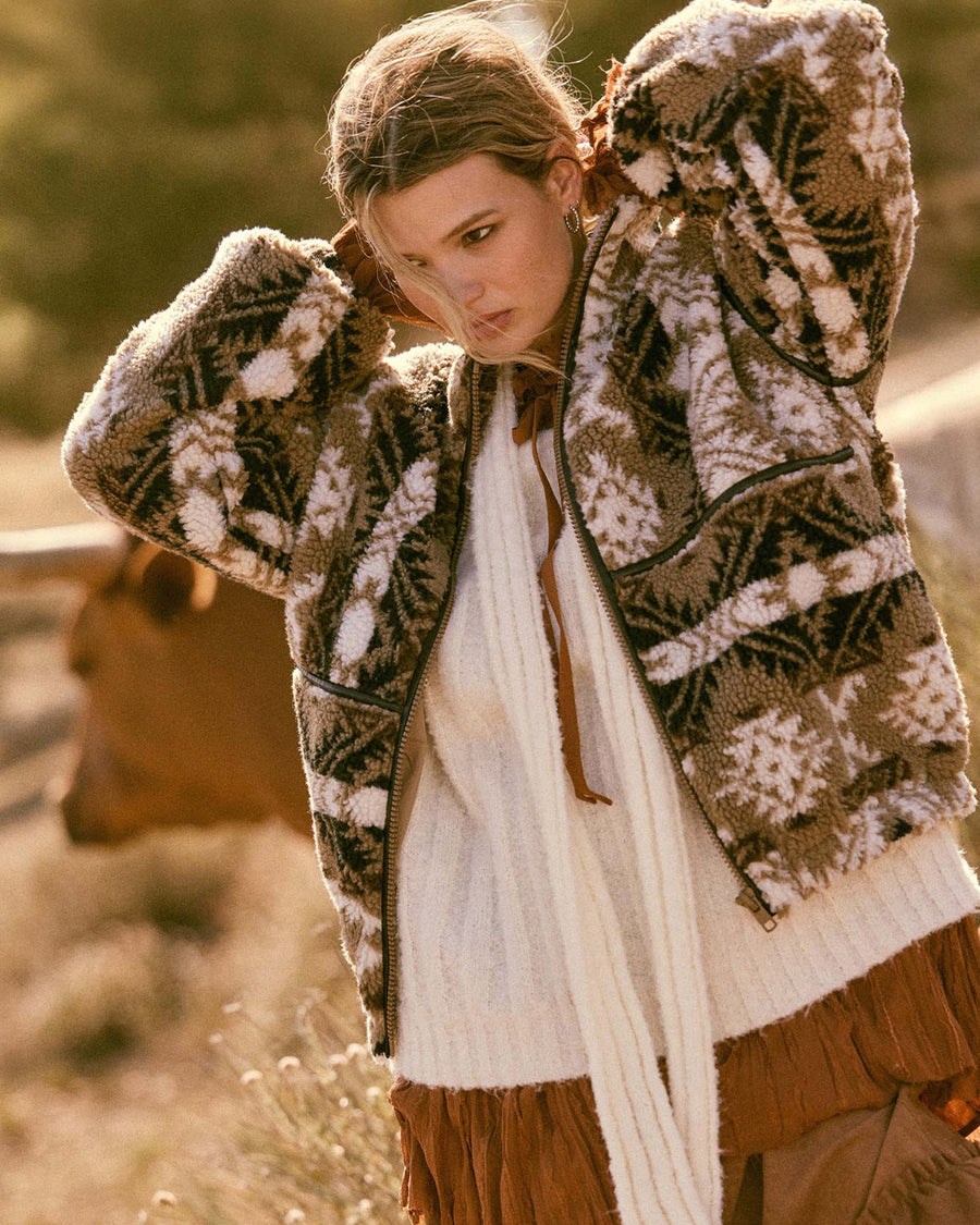 up close of model wearing brown and white geometric zip up sherpa sweatshirt with faux leather trim
