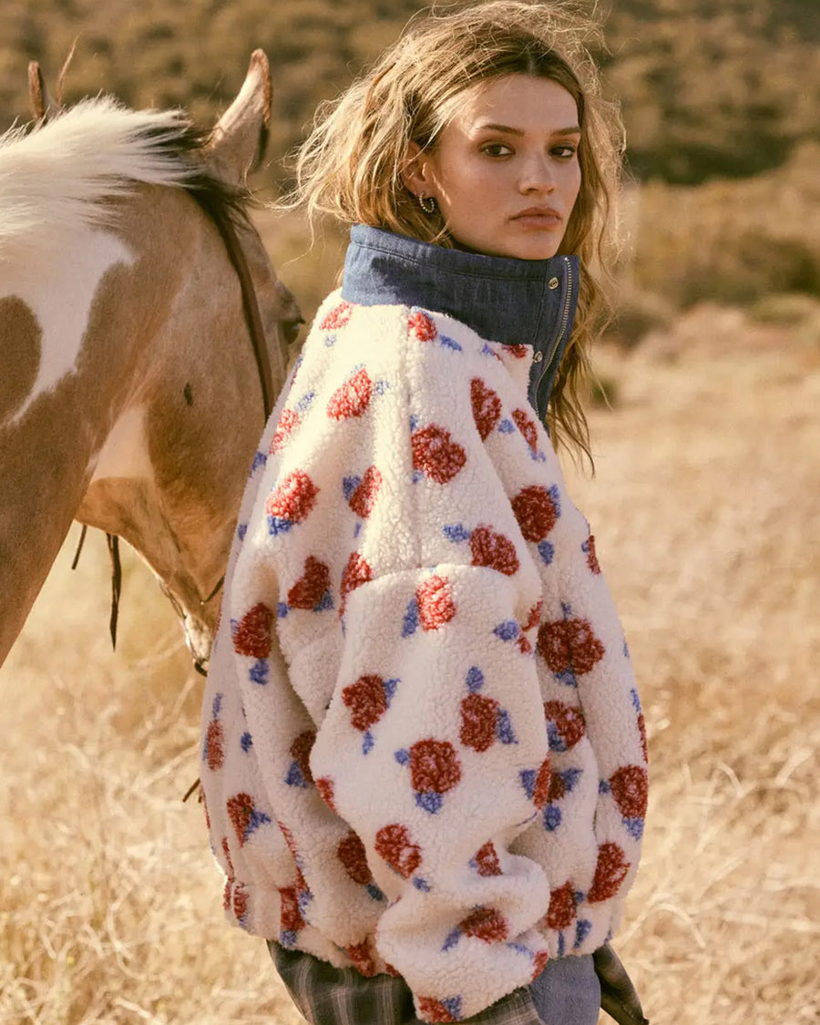 side view of model wearing white sherpa half zip with denim trim and collar and red floral print