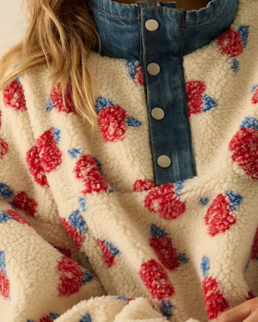 up close of model wearing white sherpa half zip with denim trim and collar and red floral print