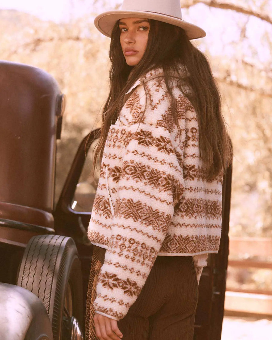 back view of model wearing cropped white zip up jacket with brown alpine print