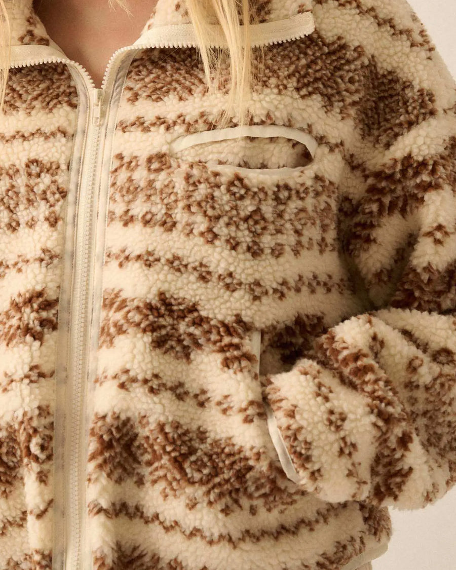 up close of model wearing cropped white zip up jacket with brown alpine print