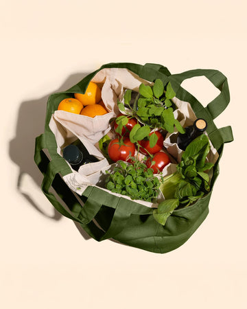 sage green cotton tote bag with various groceries inside the 6 interior pockets