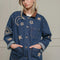 model wearing buttoned denim oversized jacket with corduroy collar, patch pockets, and embroidered star, moon and sun pattern