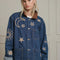 model wearing closed denim oversized jacket with corduroy collar, patch pockets, and embroidered star, moon and sun pattern