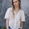 model wearing white scalloped hem blouse with slight puff sleeves and faux button front