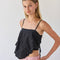 model wearing black handkerchief tank with eyelet floral detail and tie detail