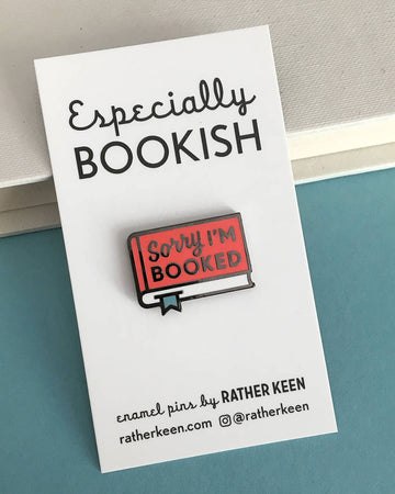 red book with 'sorry I'm booked enamel pin on cardstock