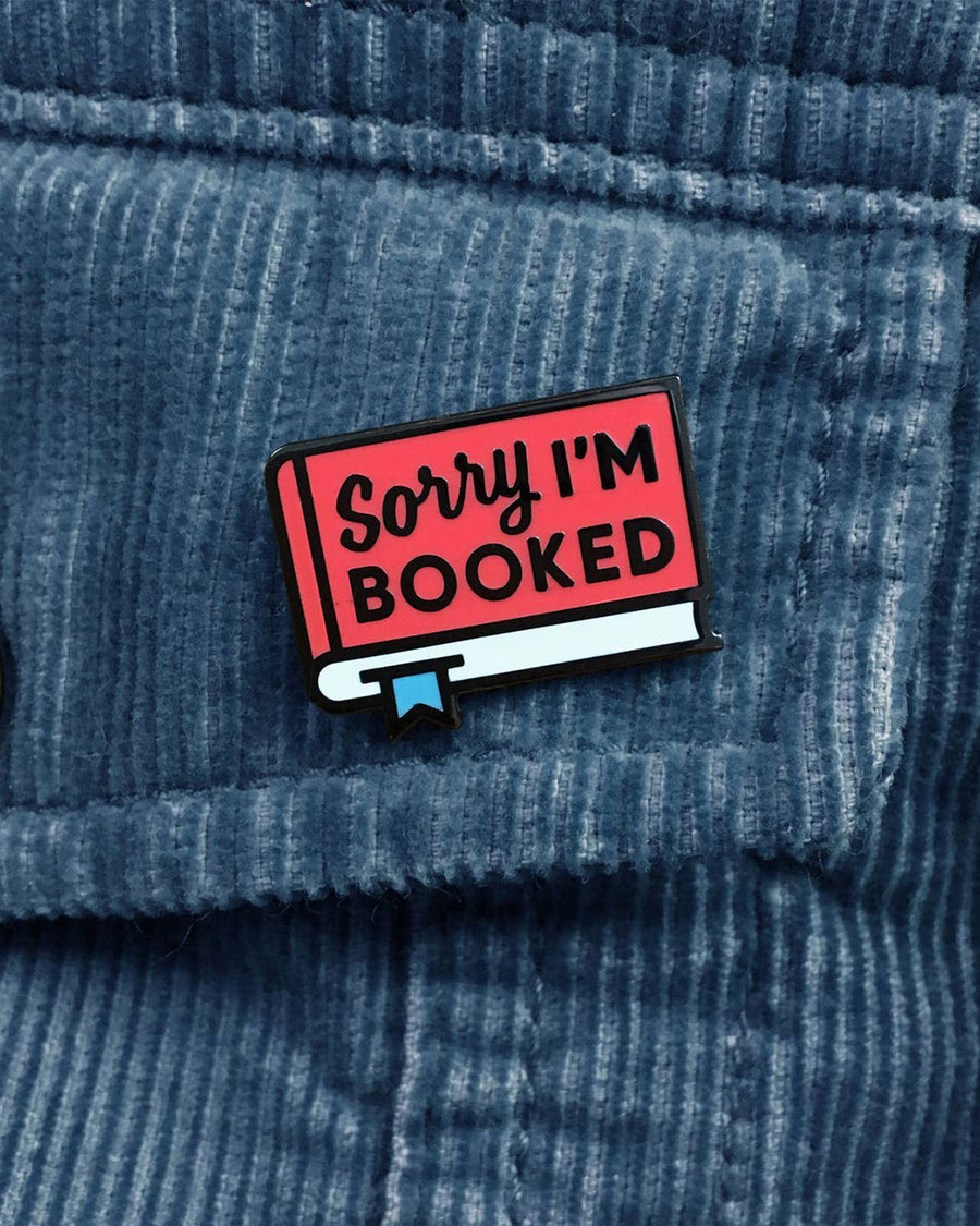 red book with 'sorry I'm booked enamel pin on jacket