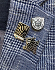 white enamel pin with grey cat and 'the book was better' across the front on blazer
