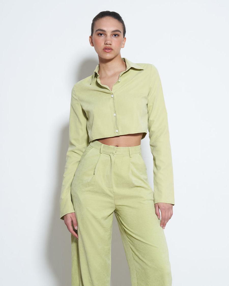 model wearing light green cropped long sleeve top with button front and collar with matching trousers