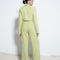 backview of model wearing light green suede trousers with pleated top and tapered legs with matching top