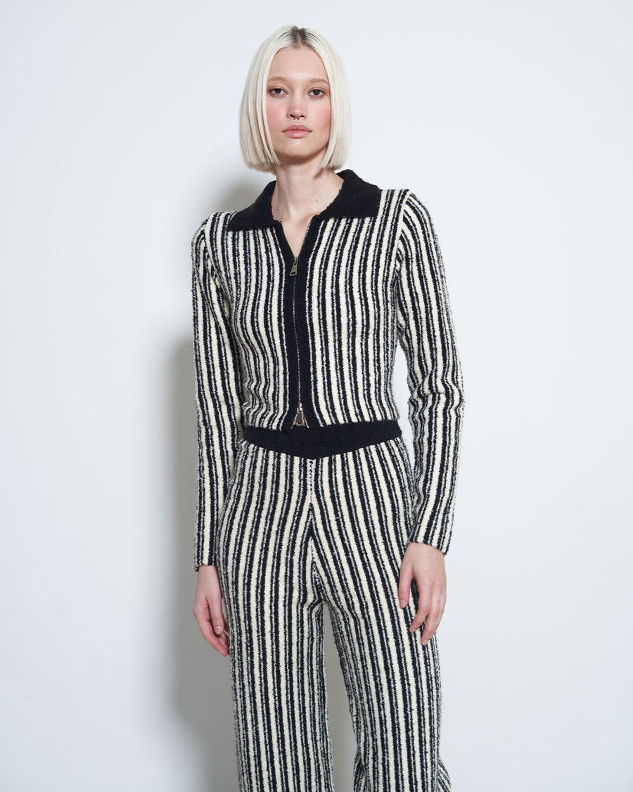 model wearing black and white vertical stripe top with collar and zipper front with matching pants