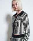 model wearing black and white vertical stripe top with collar and zipper front with matching pants