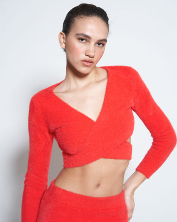 model wearing red furry knit top with criss cross waist and long sleeve