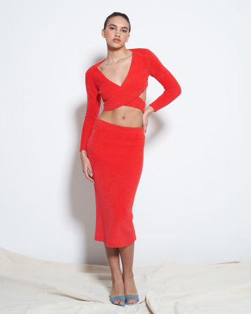 model wearing red fuzzy midi skirt with matching red criss cross top
