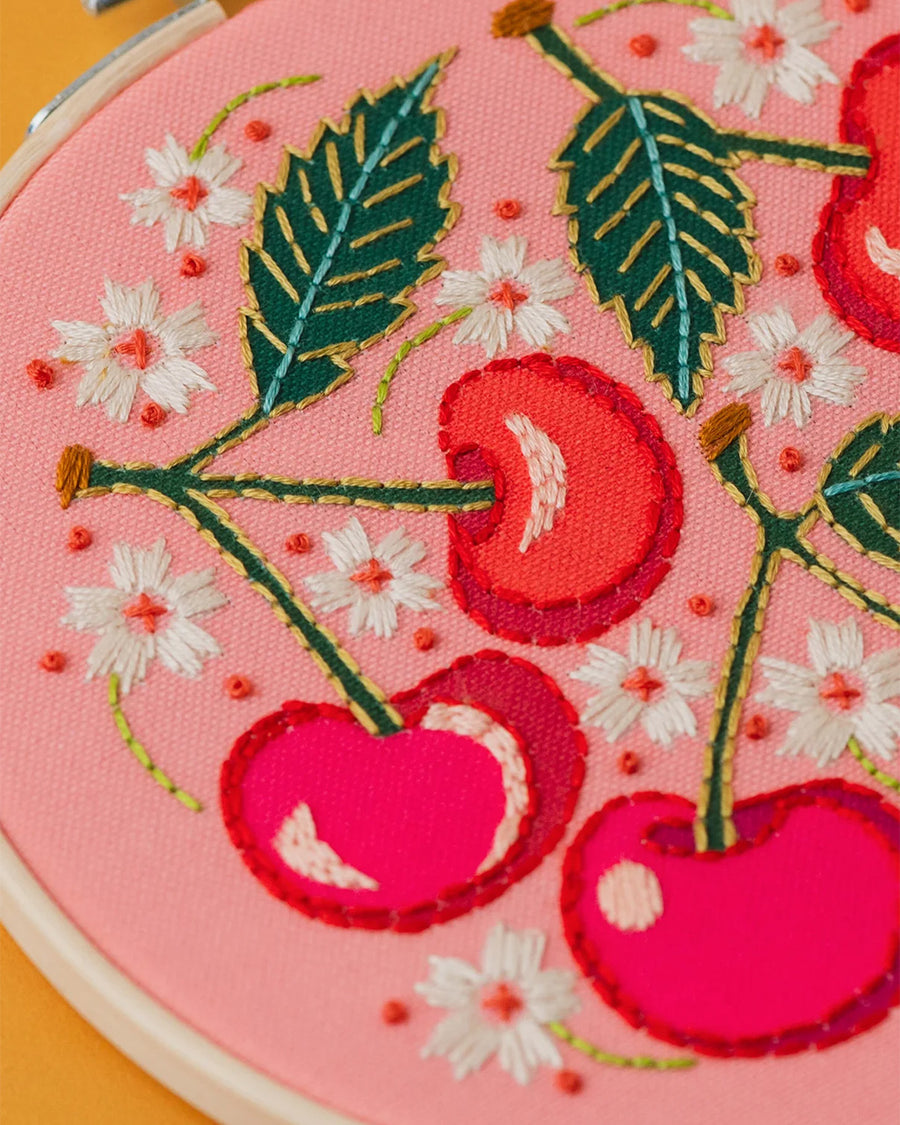 up close of pink embroidery kit with all over cherry and white flowers