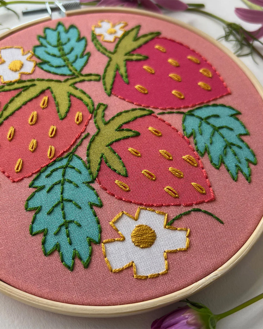 up close of pink embroidery kit with all over strawberry and strawberry leaves