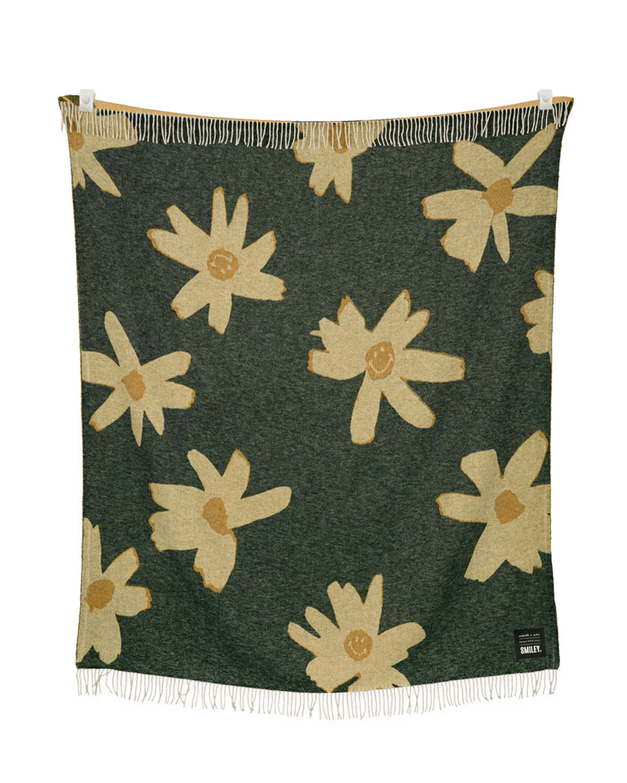 green throw blanket with yellow flower print with smiley faces in the center