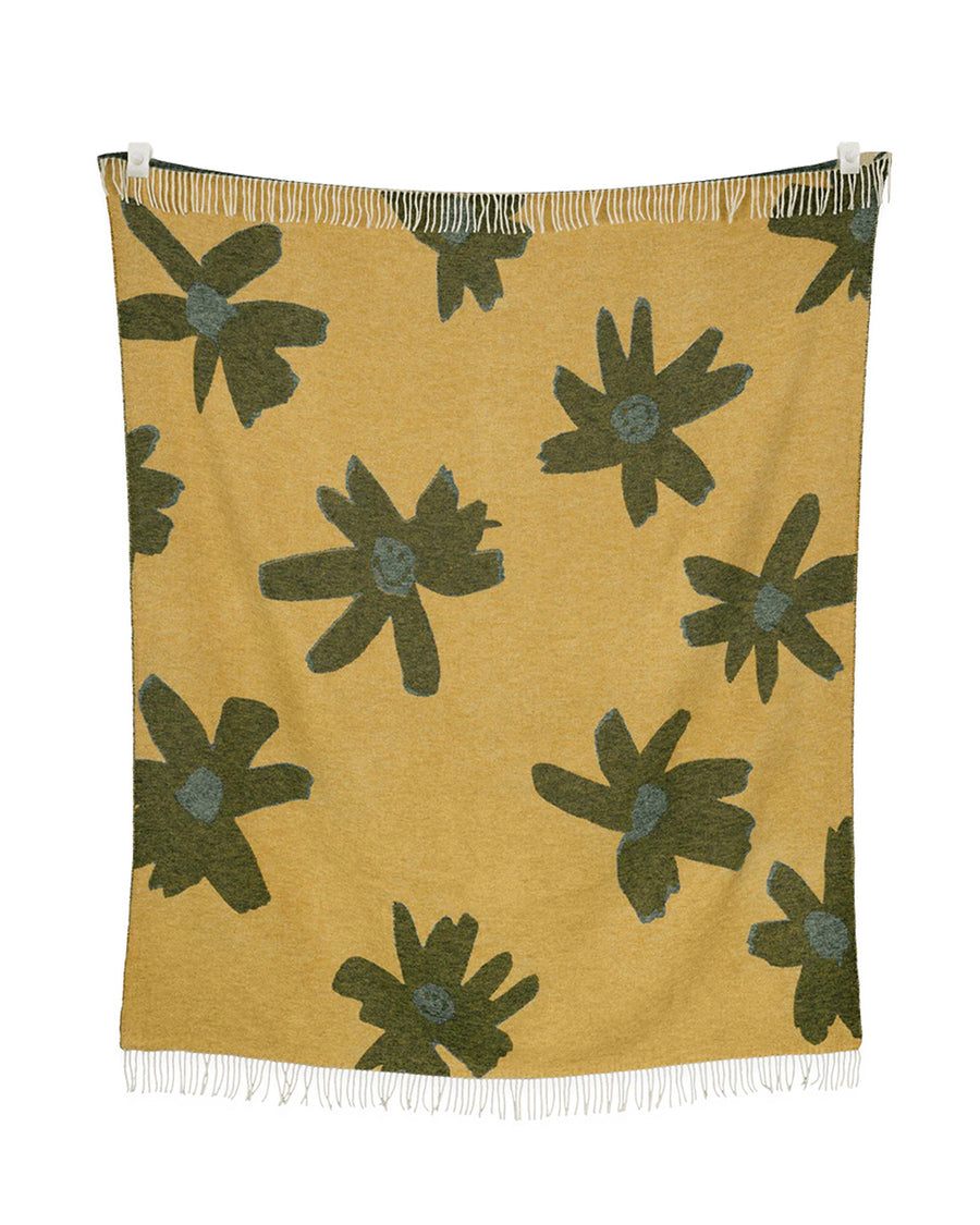 reverse side of gold throw blanket with gray flower print with smiley faces in the center