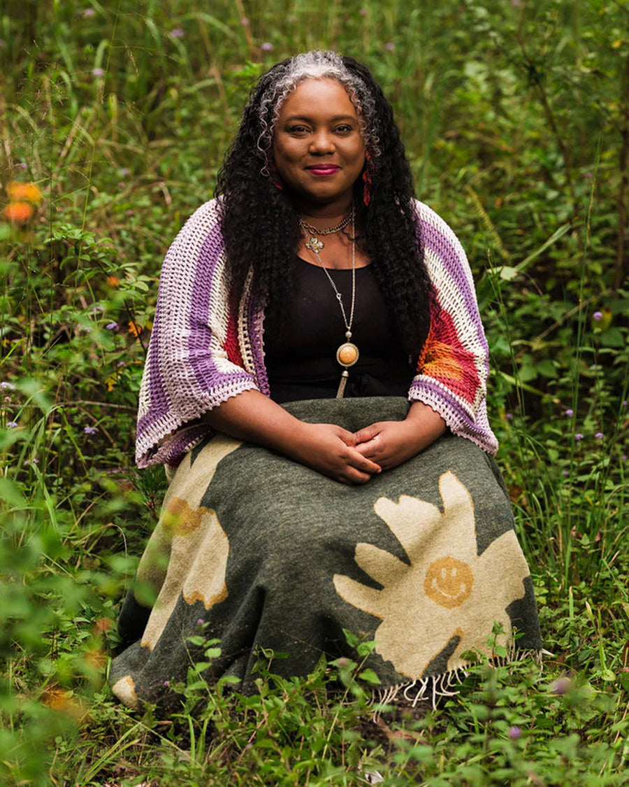model wearing green throw blanket with yellow flower print with smiley faces in the center