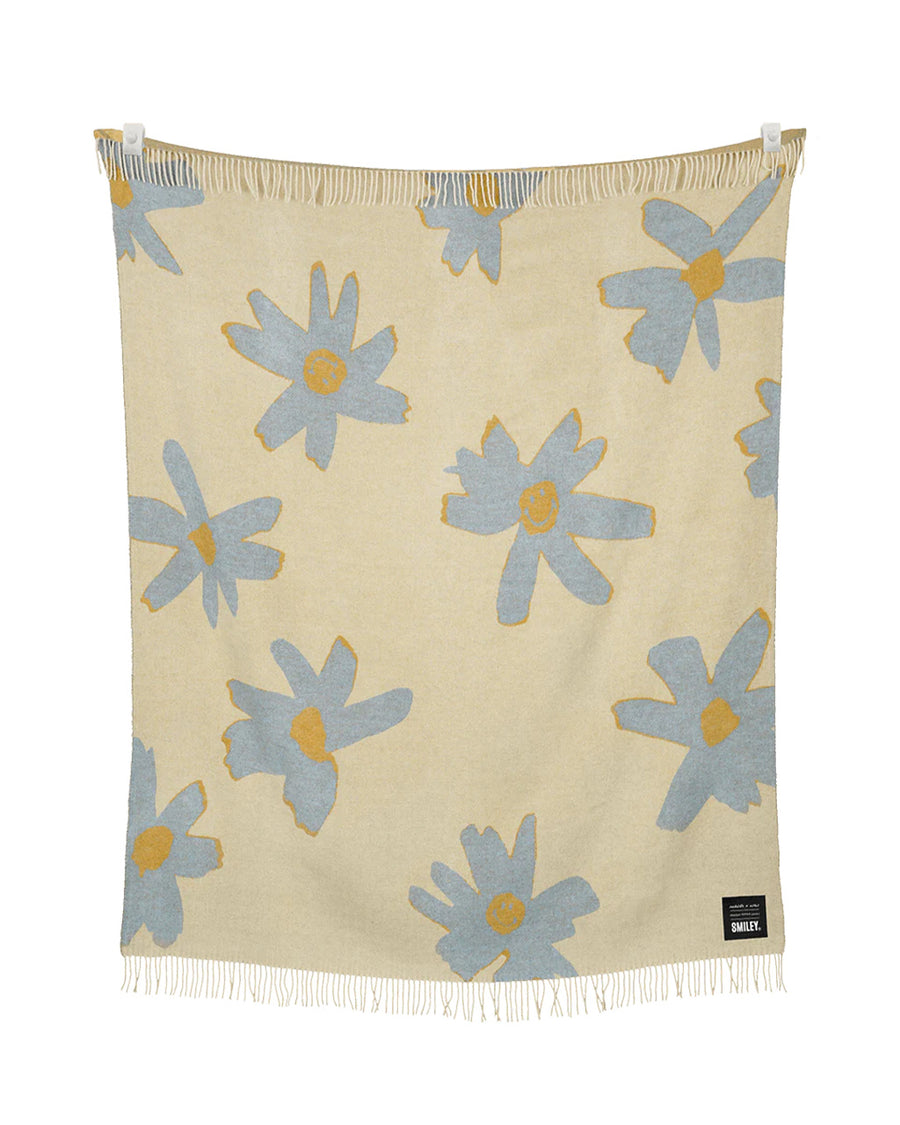 cream throw blanket with periwinkle flower print with smiley faces in the center