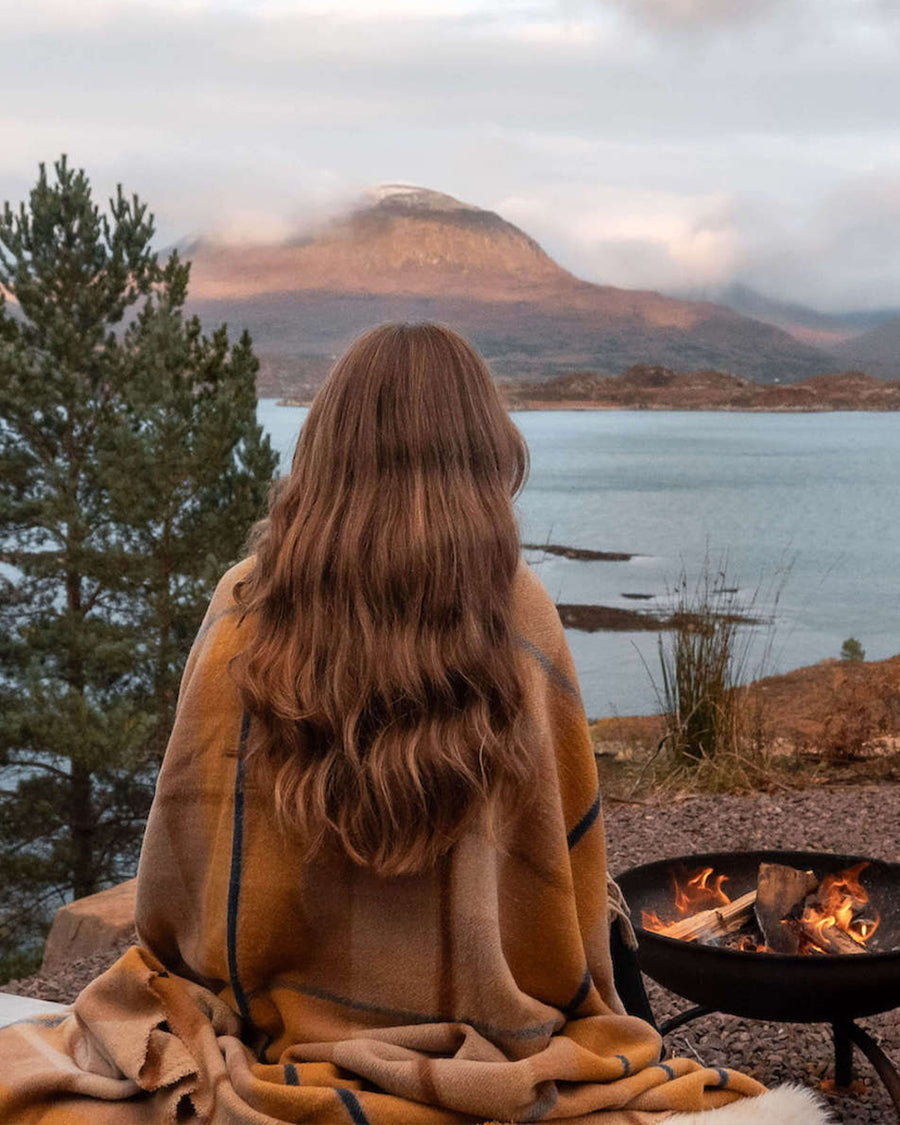 model overlooking water wrapped in orange and cream plaid throw blanket