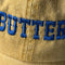 up close of pastel yellow dad hat with blue 'BUTTER' across the front