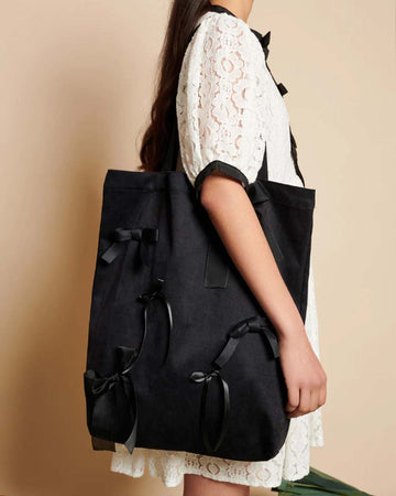model carrying black bag with matte satin, satin, and organza bows all over