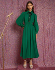 model wearing emerald green midi dress with collar, long puff sleeves, decorative button front and black tie neckline
