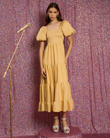 model wearing golden yellow tiered midi dress with puff sleeves, smocked bodice, and back oversized bow