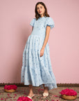 model wearing light blue tiered midi dress with puff sleeves and subtle pom detail