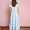 backview of model wearing light blue tiered midi dress with puff sleeves and subtle pom detail