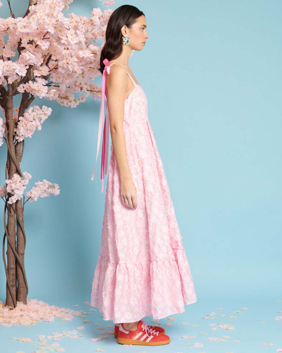 side view of model wearing pink applique midi dress with ribbon bow straps