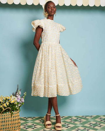model wearing light yellow jacquard midi dress with ruffle sleeves and cinched waist