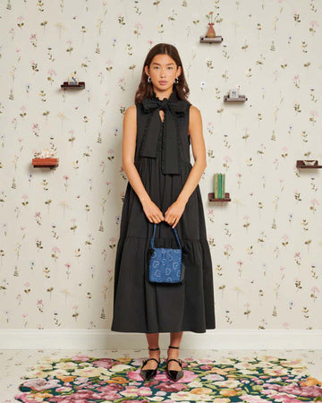 model wearing black midi dress with oversized bow neckline and tiered skirt