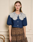 model wearing cropped dark denim top with puff sleeves and white lacy oversized collar