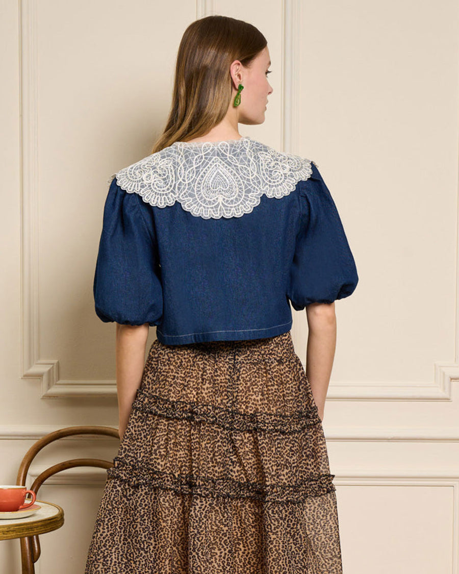 back view of model wearing cropped dark denim top with puff sleeves and white lacy oversized collar
