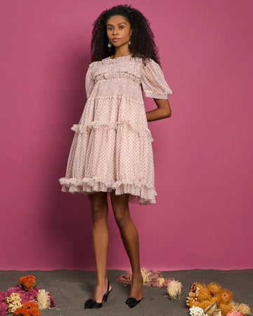 model wearing pink tulle mini dress with ruffle tiers and all over black polka dot print