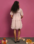 backview of model wearing pink tulle mini dress with ruffle tiers and all over black polka dot print