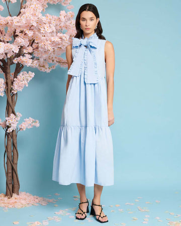 model wearing baby blue tiered midi dress with exaggerated bow neckline 